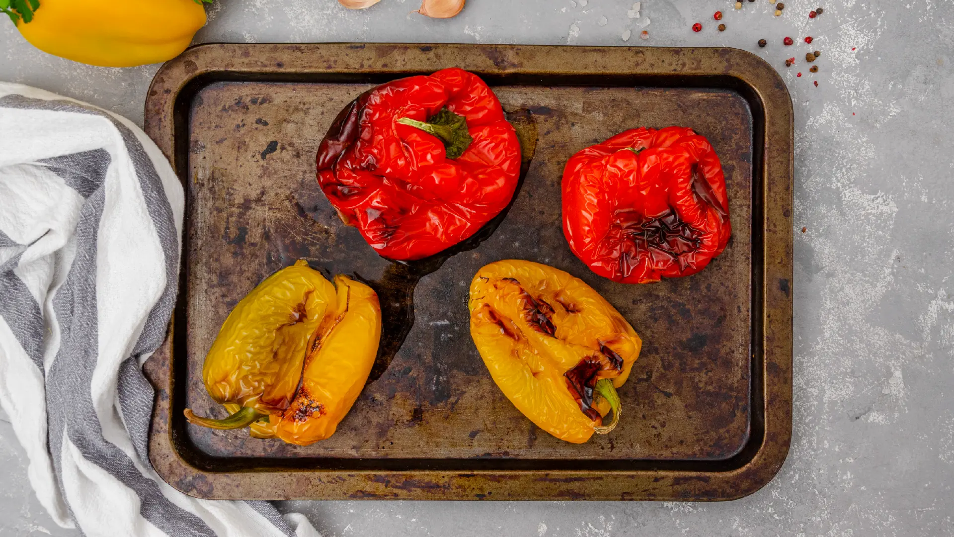 Roasted red and yellow peppers with charred skins on a rustic baking tray, prepared for a homemade burger salsa.