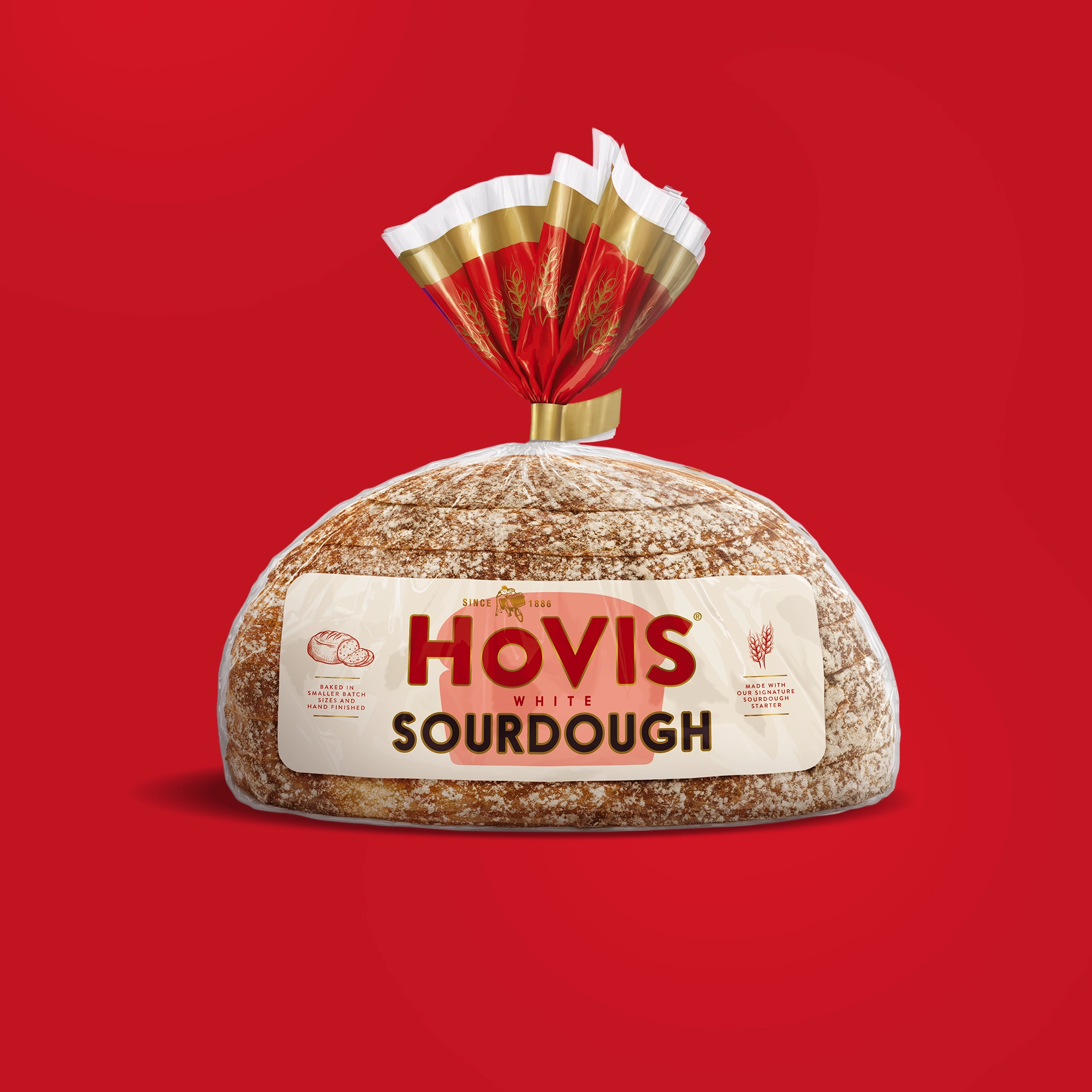 A loaf of Hovis White Sourdough bread is displayed on a red background. The packaging features a white and red design with a gold trim and nutrition information.