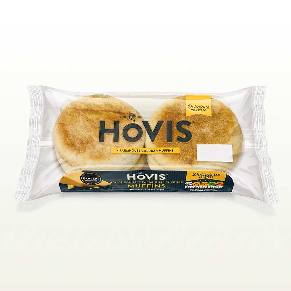Four Hovis Farmhouse Cheddar Muffins stacked in two piles of two inside a transparent rectangular packaging with the Hovis logo on top.