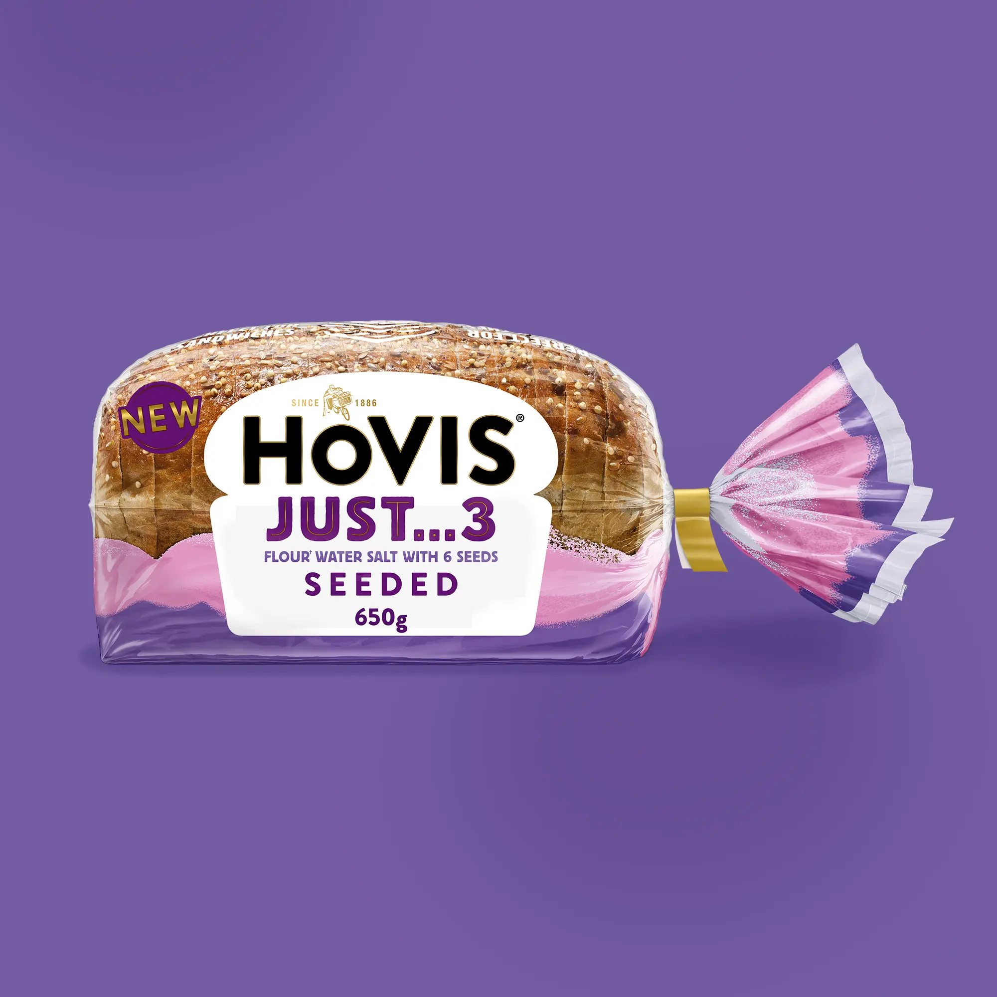 A bagged loaf of Hovis Just 3 seeded bread in clear and purple packaging with a yellow clip, on a purple background.