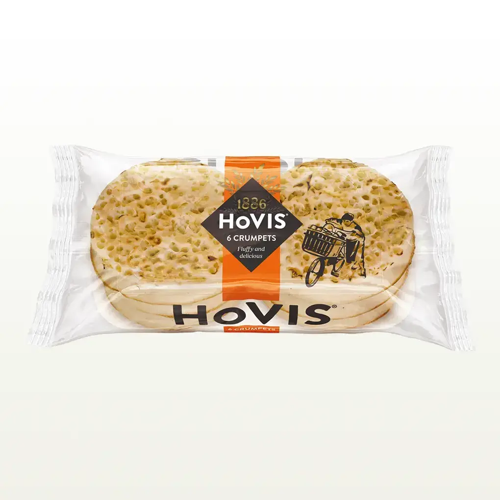Six Hovis crumpets stacked in two piles of three inside a transparent rectangular packaging with an orange stripe and the Hovis logo on top.