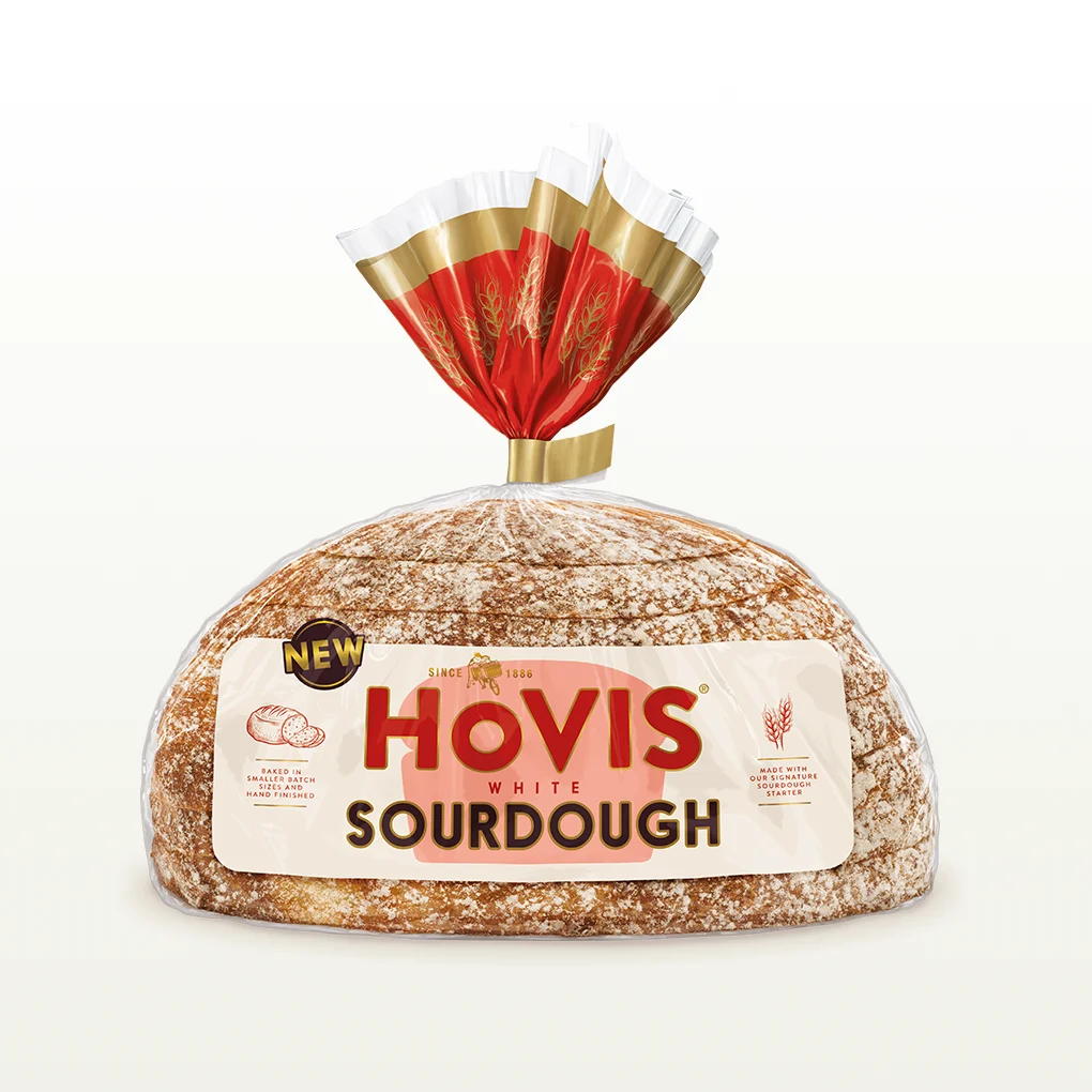 Hovis White Sourdough bread on a white backdrop with a subtle shadow. The packaging is half transparent and half light and dark red with gold detailing