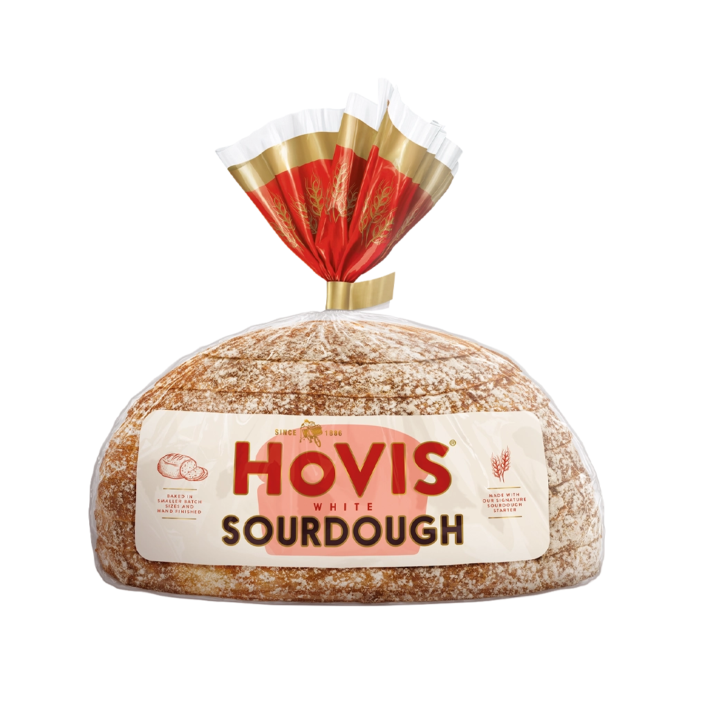 Hovis White Sourdough bread on a white backdrop with a subtle shadow. The packaging is half transparent and half light and dark red with gold detailing