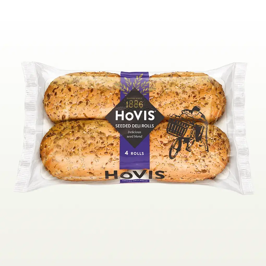 Four Hovis 4 Seeded Deli Rolls in a transparent rectangular packaging featuring the Boy on the Bike, a purple strip, golden wheat, and the Hovis logo on top.